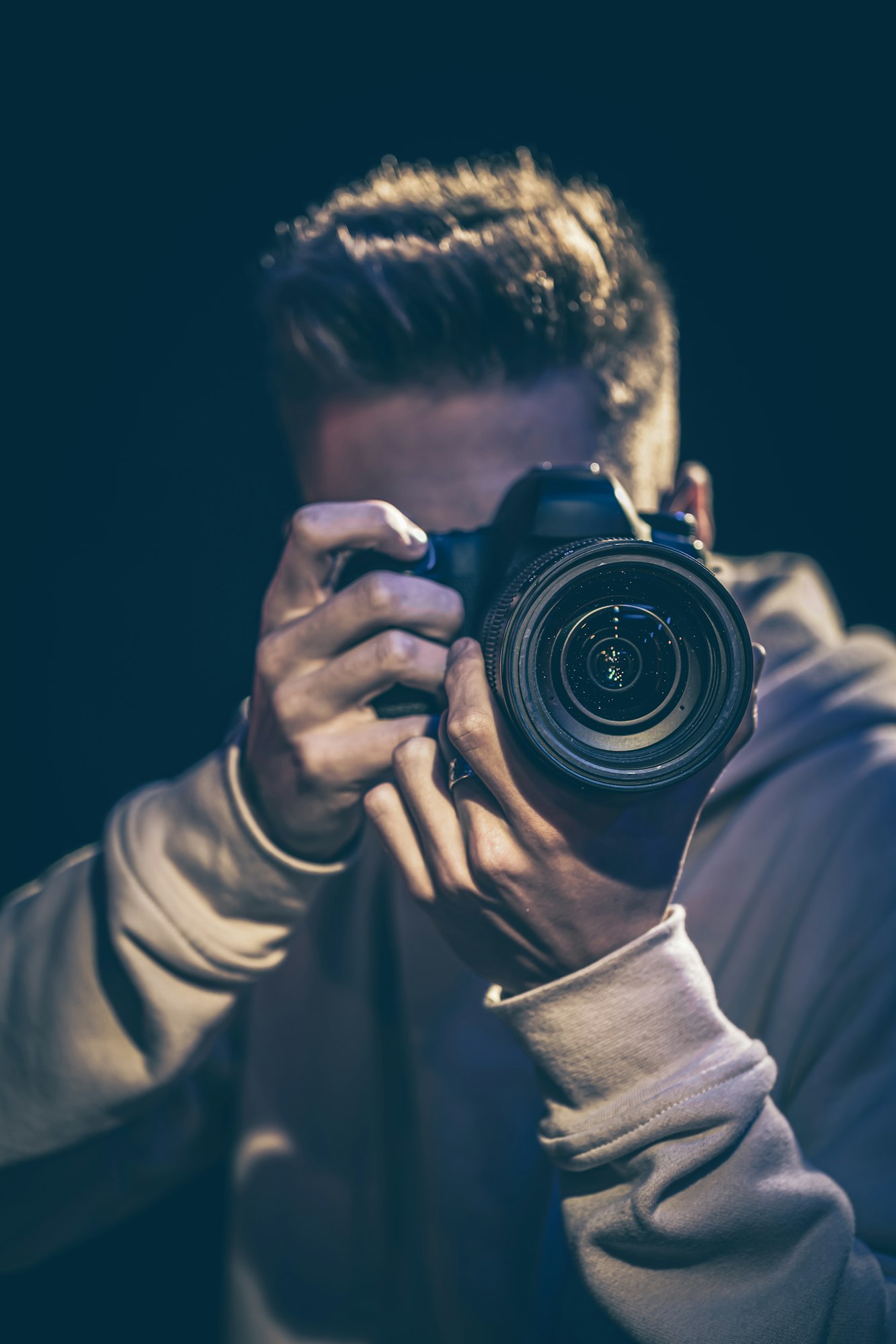 A man photographer with a camera takes a photo in the dark.